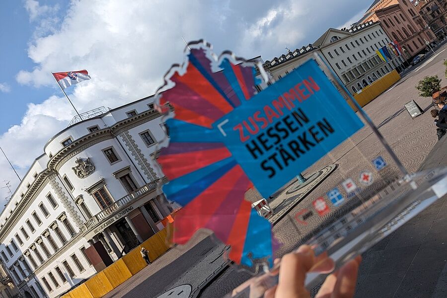 Unser Kampagnenlogo im Vordergrund, der Hessische Landtag im Hintergrund